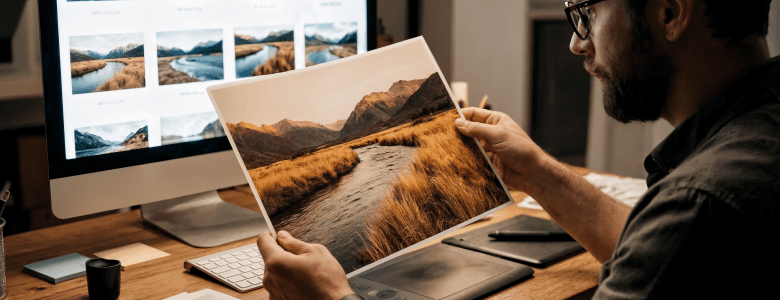 Man reviewing a custom art print while ordering prints online on a desktop